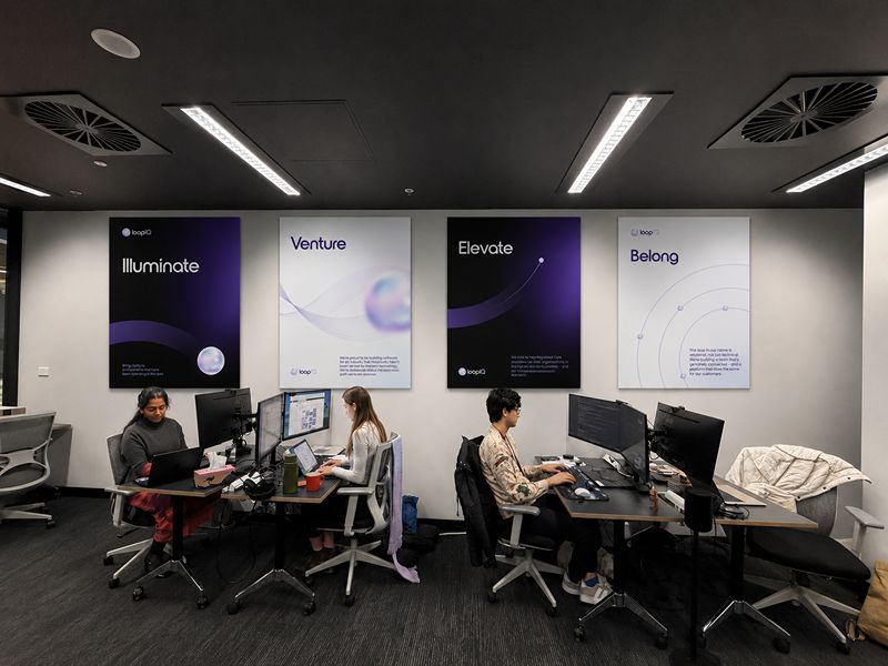 Branded office interior featuring illuminated wall posters and workstation displays.